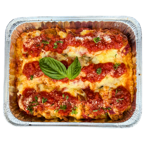 Family size Chicken Parmigiana in a foil container, topped with cheese and tomato sauce, garnished with a basil leaf.