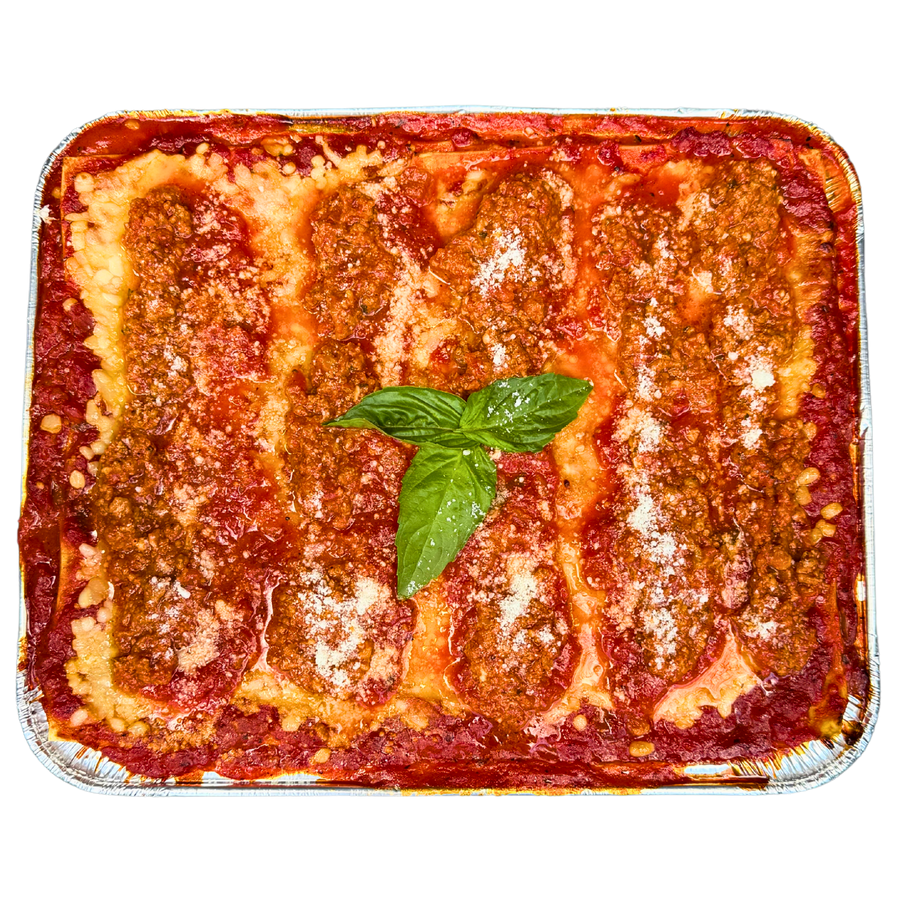 A family size tray of Lasagna Bolognese with layers of pasta and sauce, garnished with a basil leaf.